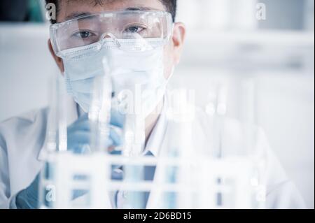 Scienziato maschile asiatico che lavora in un laboratorio. Concetto di sviluppo del vaccino. Foto Stock