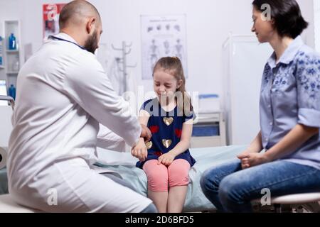 Ragazza che ha dolori a causa del braccio durante il check-up medico in ospedale ufficio. Medico specialista in medicina che fornisce servizi di assistenza sanitaria esame di trattamento. Foto Stock