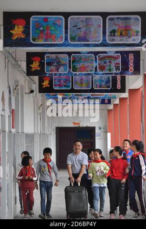 (201016) -- LUXI, 16 ottobre 2020 (Xinhua) -- li Xuezhan (C) cammina con la sua valigia contenente sussidi didattici fatti a mano a scuola nella contea di Luxi, nella provincia di Jiangxi della Cina orientale, 14 ottobre 2020. Ogni volta che li Xuezhan entra nella scuola centrale nella città di Xuanfeng della contea di Luxi con la sua valigia piena di sussidi didattici fatti a mano, sarà seguito e circondato da studenti. Li, 58 anni, divenne insegnante di scienze nel 1996. A causa della mancanza di ausili didattici, ha dovuto raccogliere bottiglie vuote, legno, pneumatici rotti e trasformarli in ausili didattici per la classe scientifica. Ora come condizionati di insegnamento della scuola Foto Stock