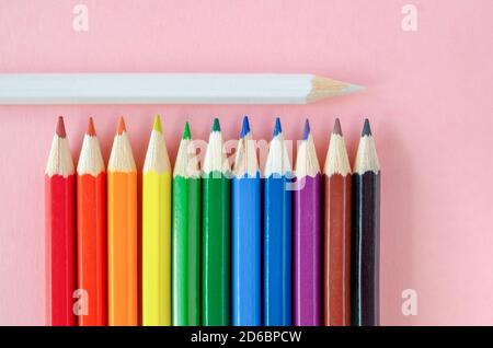 Diverse matite multicolore sono disposte su uno sfondo rosa. Foto Stock