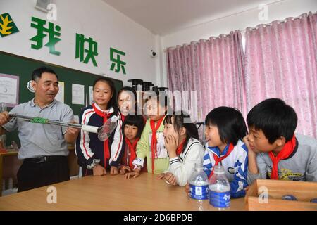 (201016) -- LUXI, 16 ottobre 2020 (Xinhua) -- li Xuezhan (1st L) dimostra un dispositivo di prelievo fatto a mano in classe nella contea di Luxi, nella provincia di Jiangxi della Cina orientale, 14 ottobre 2020. Ogni volta che li Xuezhan entra nella scuola centrale nella città di Xuanfeng della contea di Luxi con la sua valigia piena di sussidi didattici fatti a mano, sarà seguito e circondato da studenti. Li, 58 anni, divenne insegnante di scienze nel 1996. A causa della mancanza di ausili didattici, ha dovuto raccogliere bottiglie vuote, legno, pneumatici rotti e trasformarli in ausili didattici per la classe scientifica. Ora come le condizioni di insegnamento della scuola sono migliorate Foto Stock