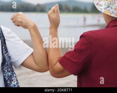 Due donne alternative handshakes Elbow Bump saluto nella situazione di un'epidemia covid 19, coronavirus nuovo normale di allontanamento sociale Foto Stock