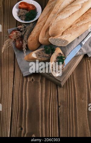 Vista dall'alto baguette fresche alla francese affettate con pomodoro foie gras e prezzemolo su un tavolo di legno Foto Stock