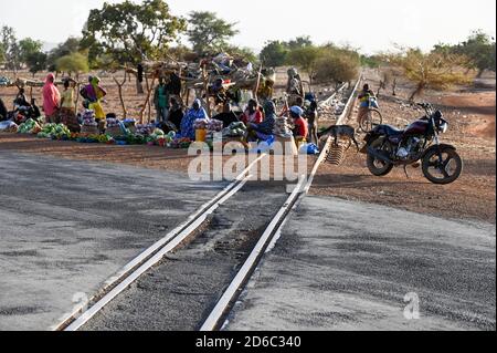 BURKINA FASO, Kaya, linea ferroviaria abbandonata per le miniere di minerale di manganese a Tambao, costruito durante il tempo di Thomas Sankara, persone che vendono ortaggi al passaggio ferroviario stradale / BURKINA FASO, Kaya, von Sankara gebaute Eisenbahnzu Linie den Mangan Lagerstätten a Tambao, Eisenbahnstrecke schon seit Jahren ausser Betrieb, Menschen verkaufen Gemüse und Obst an einem Bahnübergang Foto Stock