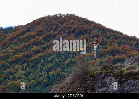 Crocifisso contro le montagne boscose, Ariege, Pirenei francesi, Francia, Pirenei in autunno Foto Stock