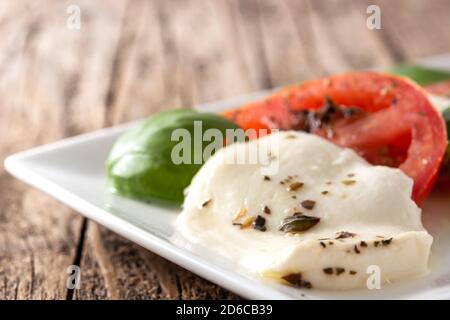 Insalata tradizionale di caprese con pomodoro e mozzarella in stile rustico tavolo di legno Foto Stock