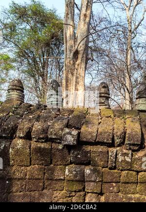 Recinzione rovine albero giungla Prasat Krahom mattoni rossi Tempio indù a Koh Ker. Muschio sulla pietra mattoni di arenaria laterite blocchi archeologici Paesaggio o Foto Stock