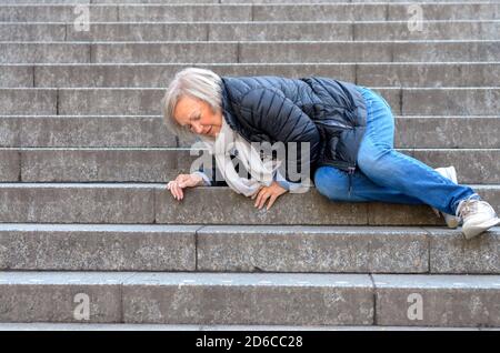 Senior donna accidentaly cadendo gradini in pietra all'aperto Foto Stock
