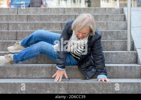 Senior donna accidentaly cadendo gradini in pietra all'aperto Foto Stock