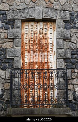 Vecchie persiane danneggiate e arrugginite sul balcone di un edificio in pietra. Foto Stock