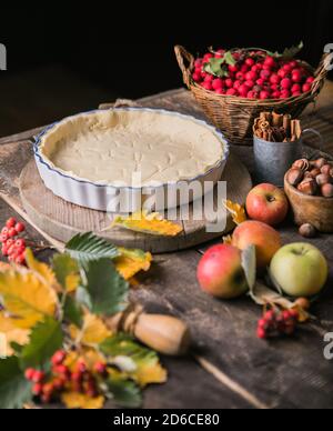 Sfondo da forno con torta di mele classica cruda, ingredienti da forno e utensili. Torta fatta in casa circondata da frutta fresca Foto Stock