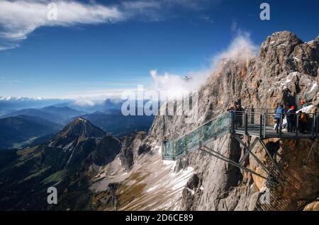 I turisti si trovano sulla piattaforma di osservazione del ponte di corda dello Skywalk Dachstein Montagne e gode del paesaggio in Austria Foto Stock