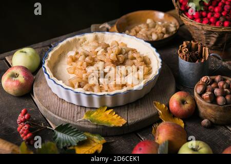 Sfondo da forno con torta di mele classica cruda, ingredienti da forno e utensili. Torta fatta in casa circondata da frutta fresca Foto Stock