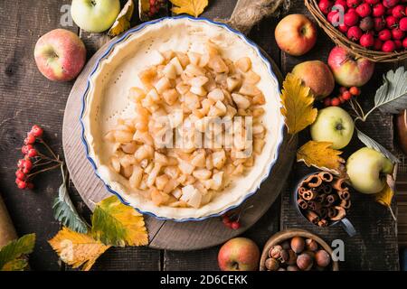 Sfondo da forno con torta di mele classica cruda, ingredienti da forno e utensili. Torta fatta in casa circondata da frutta fresca Foto Stock