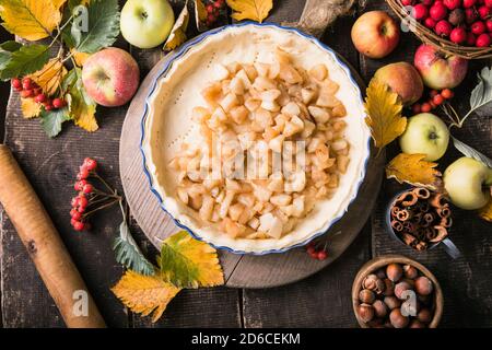 Sfondo da forno con torta di mele classica cruda, ingredienti da forno e utensili. Torta fatta in casa circondata da frutta fresca Foto Stock