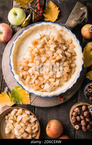 Sfondo da forno con torta di mele classica cruda, ingredienti da forno e utensili. Torta fatta in casa circondata da frutta fresca Foto Stock