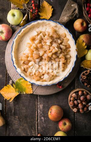 Sfondo da forno con torta di mele classica cruda, ingredienti da forno e utensili. Torta fatta in casa circondata da frutta fresca Foto Stock