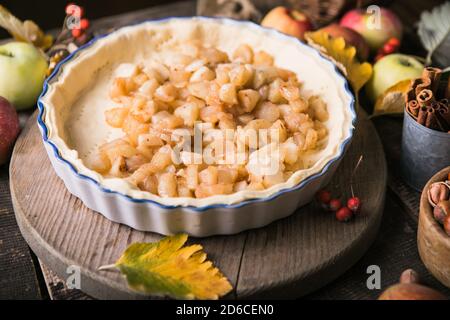 Sfondo da forno con torta di mele classica cruda, ingredienti da forno e utensili. Torta fatta in casa circondata da frutta fresca Foto Stock