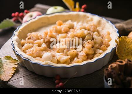 Sfondo da forno con torta di mele classica cruda, ingredienti da forno e utensili. Torta fatta in casa circondata da frutta fresca Foto Stock