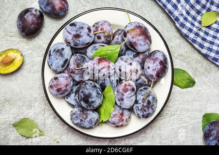 Un sacco di prugne dolci fresche in un piatto con foglie, vista dall'alto con spazio per il testo. Frutta sana. Foto Stock