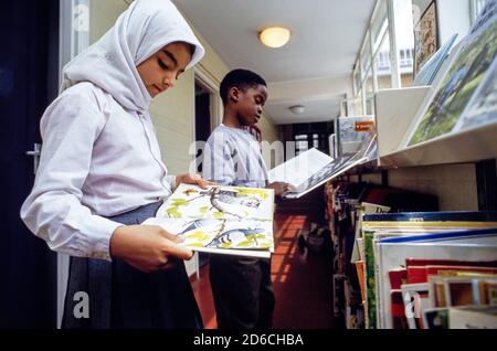 Gli studenti navigano nei libri della biblioteca della scuola elementare Christchurch CoFe di Londra NW1. 02 luglio 1991. Foto: Neil Turner Foto Stock