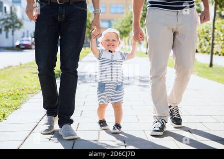 Bambino che cammina con i padri Foto Stock