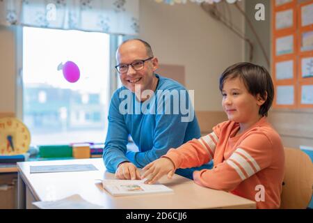 Insegnante che aiuta il ragazzo in classe Foto Stock