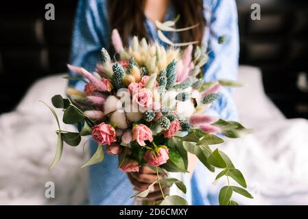 Bouquet nuziale primo piano. Ragazza in un vestito blu tiene un mazzo di fiori in mano Foto Stock