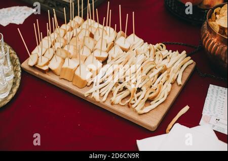 Vista laterale di una tavola di legno con pezzi a fette di diversi tipi di formaggio su spiedini. Catering. Foto Stock