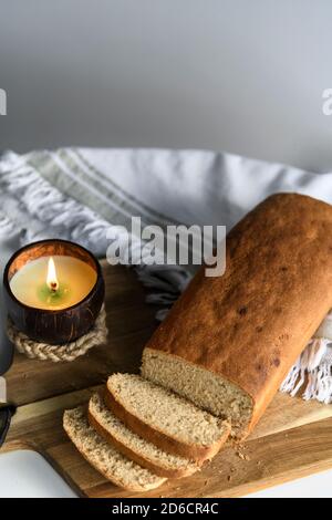 Pane fatto in casa a fette su un tagliere di legno con un candela su un tovagliolo bianco Foto Stock