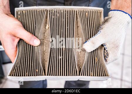 La mano di mechanik tiene il vecchio filtro dell'aria dell'automobile Foto Stock