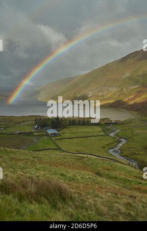 Arcobaleno vivido attraverso il bacino idrico di Talla in autunno, confini scozzesi. Foto Stock