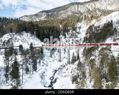 Filisur Svizzera - Gennaio 31. 2019: Un treno svizzero per passeggeri rossi che passa sul viadotto Schmitten, che si trova sulla stessa linea con il Viaduc Landwasser Foto Stock