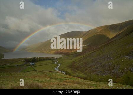 Arcobaleno vivido attraverso il bacino idrico di Talla in autunno, confini scozzesi. Foto Stock