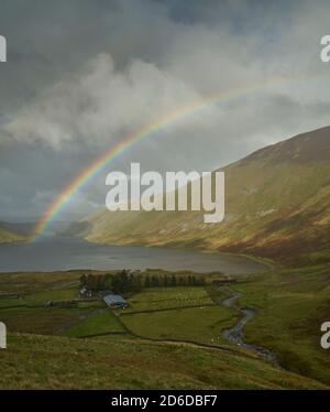 Arcobaleno vivido attraverso il bacino idrico di Talla in autunno, Scottish Borders.nuvoloso Foto Stock