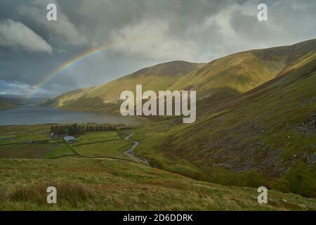 Arcobaleno vivido attraverso il bacino idrico di Talla in autunno, Scottish Borders.nuvoloso Foto Stock