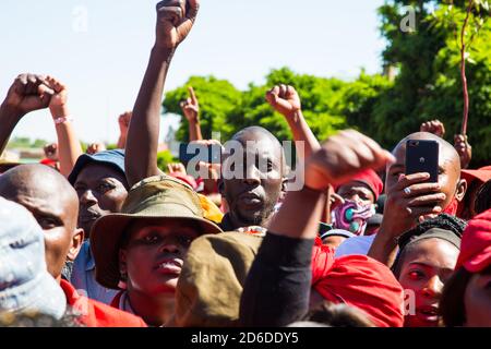 I membri dei combattenti per la libertà economica (EFF) e i sostenitori di Julius Malema fanno gesti mentre si levano fuori dalla corte dei magistrati durante la protesta. UN confronto teso tra agricoltori bianchi e attivisti neri ha afferrato la città sudafricana di Senekal, come due uomini accusati di aver ucciso un manager bianco fattoria dovevano comparire in tribunale. Più di 100 poliziotti hanno pattugliato l'area di fronte al tribunale della provincia dello Stato libero e hanno utilizzato il filo spinato per separare i gruppi rivali. Foto Stock