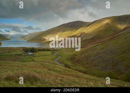 Arcobaleno vivido attraverso il bacino idrico di Talla in autunno, Scottish Borders.nuvoloso Foto Stock