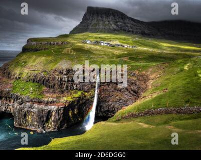 Una vista sulla cascata Mulafossur a Gasadalur, isole Faroe con piccolo arcobaleno. Foto Stock