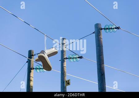 un paio di sneaker pendono su una linea elettrica Foto Stock