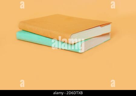 Due libri con copertine colorate sono su un arancione uniforme sfondo Foto Stock