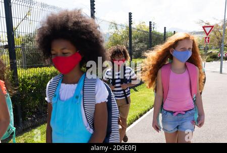 Gruppo di bambini che indossano maschere che camminano sulla strada Foto Stock