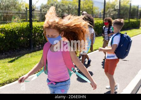 Gruppo di bambini che indossano maschere a piedi sul sentiero Foto Stock