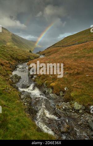 Arcobaleno vivido attraverso il bacino idrico di Talla in autunno, confini scozzesi. Foto Stock