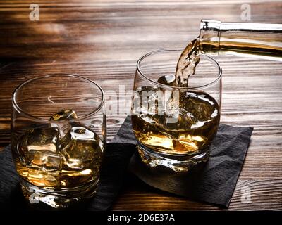 Due glasi di whiskey, una riempita da una bottiglia Foto Stock