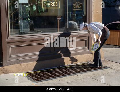 Un operaio per il ristorante Harbs nel quartiere Chelsea di New York prepara gli adesivi di distanza sociale giovedì 8 ottobre 2020. (© Richard B. Levine) Foto Stock