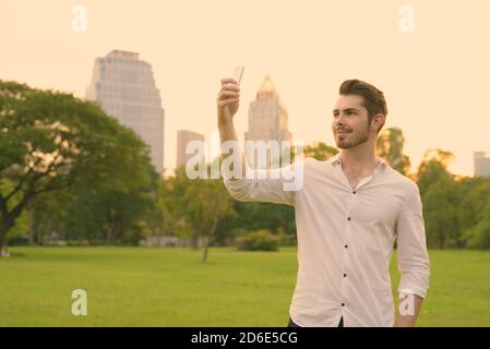 Ritratto di giovane uomo bello rilassarsi presso il parco Foto Stock