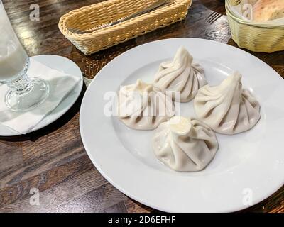 Khinkali caldi e succosi con carne ed erbe su piatto bianco. Foto Stock