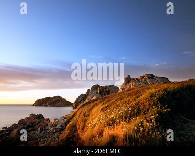 Costa rocciosa in Bretagna. Tramonto sul mare Foto Stock