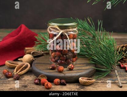 Un vasetto di fianchi di rose asciutti su sfondo natalizio. Foto Stock